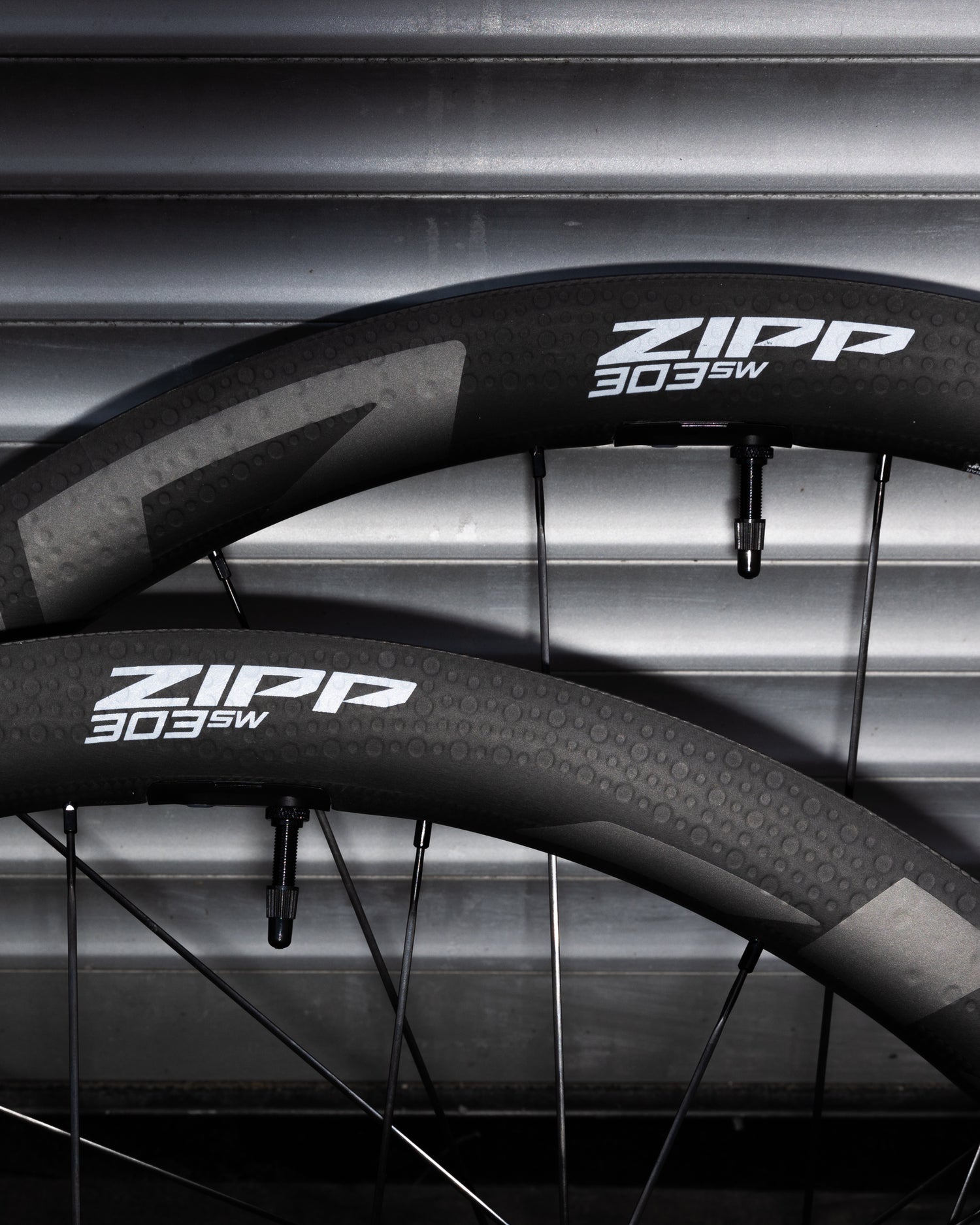 Two Zipp 303SW bicycle wheels on a metallic background